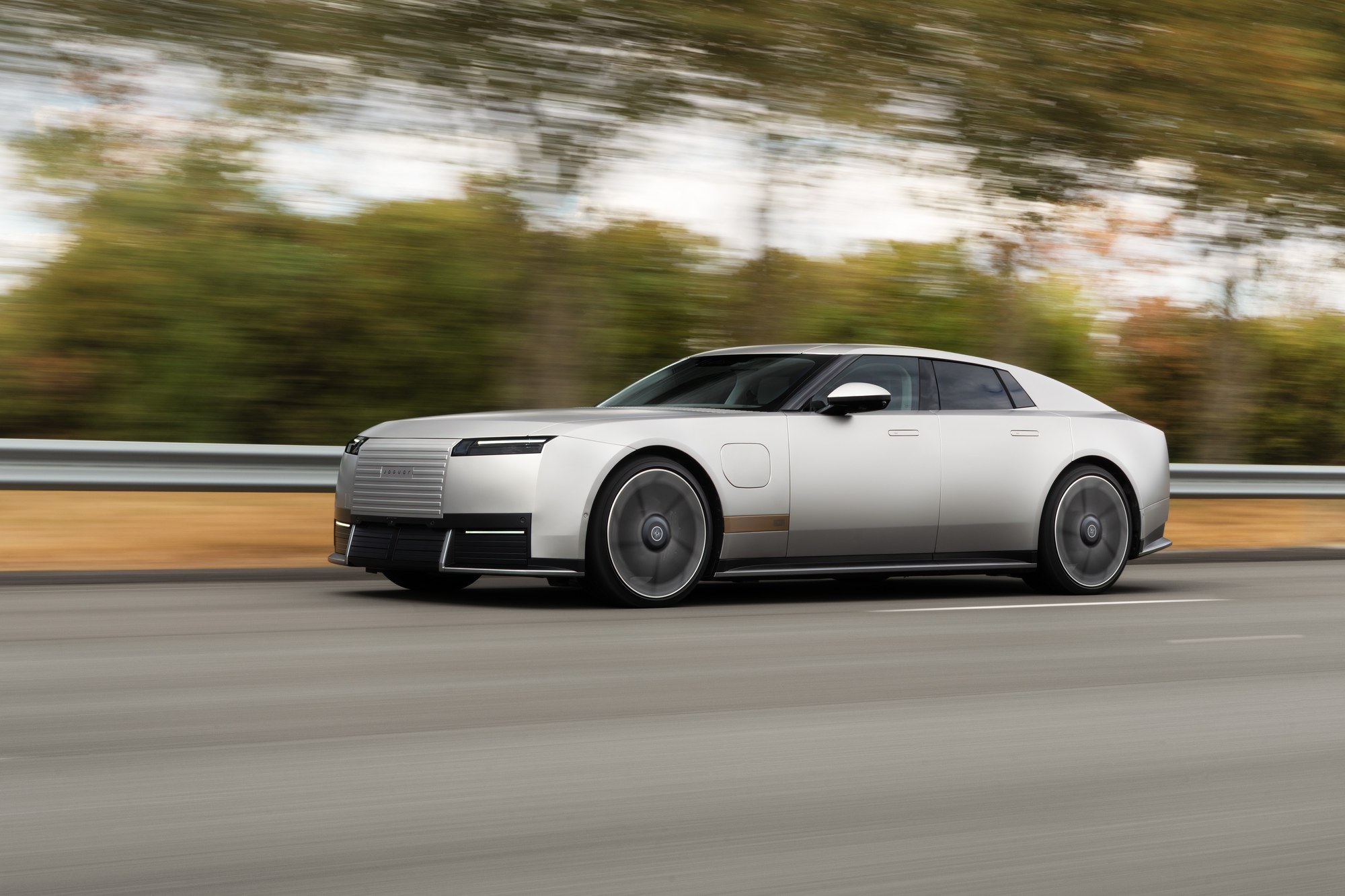 Silver Jaguar Type 01 electric four-door GT in a front three-quarter view on a road.