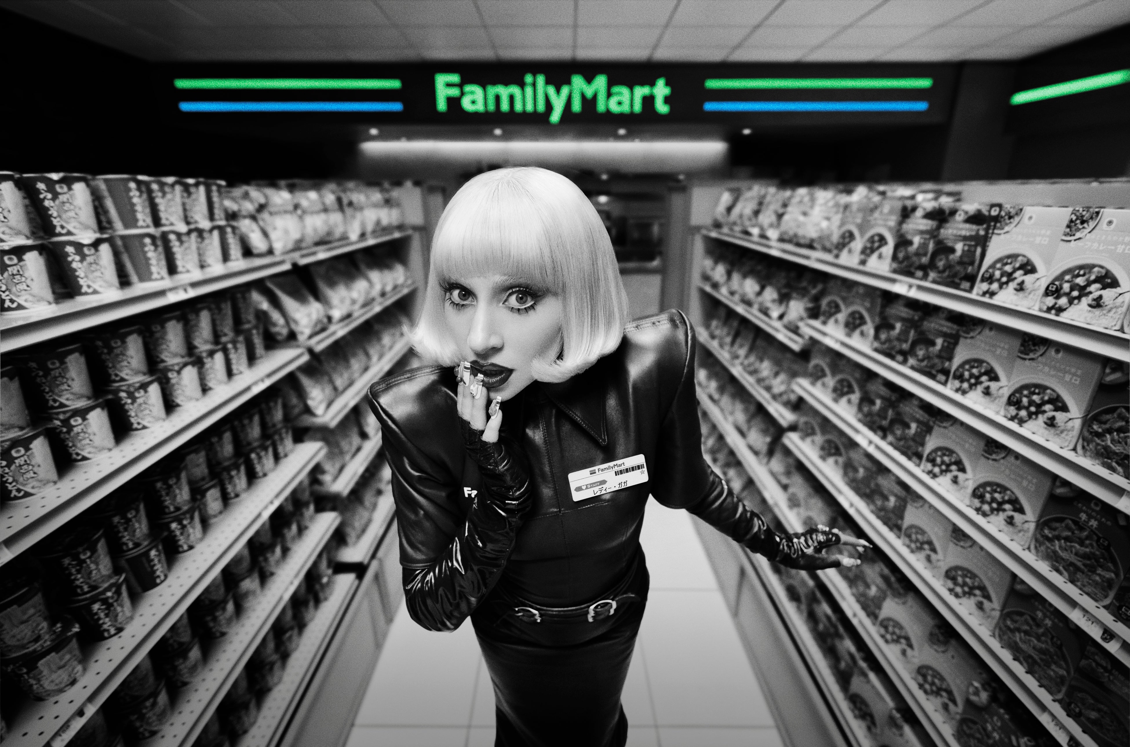 Lady Gaga in a black couture FamilyMart uniform and name badge poses in a convenience-store aisle beneath the FamilyMart sign.