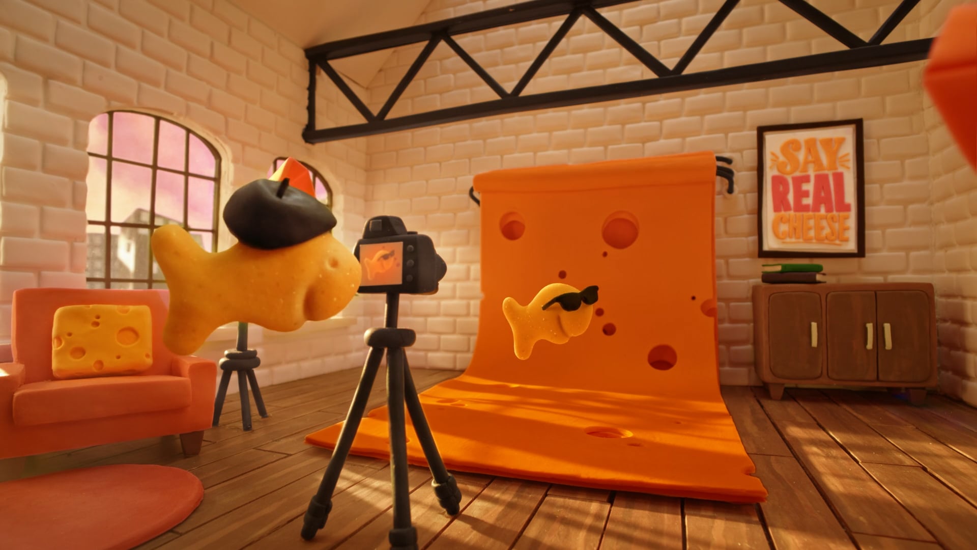 A smiling Goldfish snack wearing sunglasses poses before a camera against a backdrop made to look like a slice of cheese.