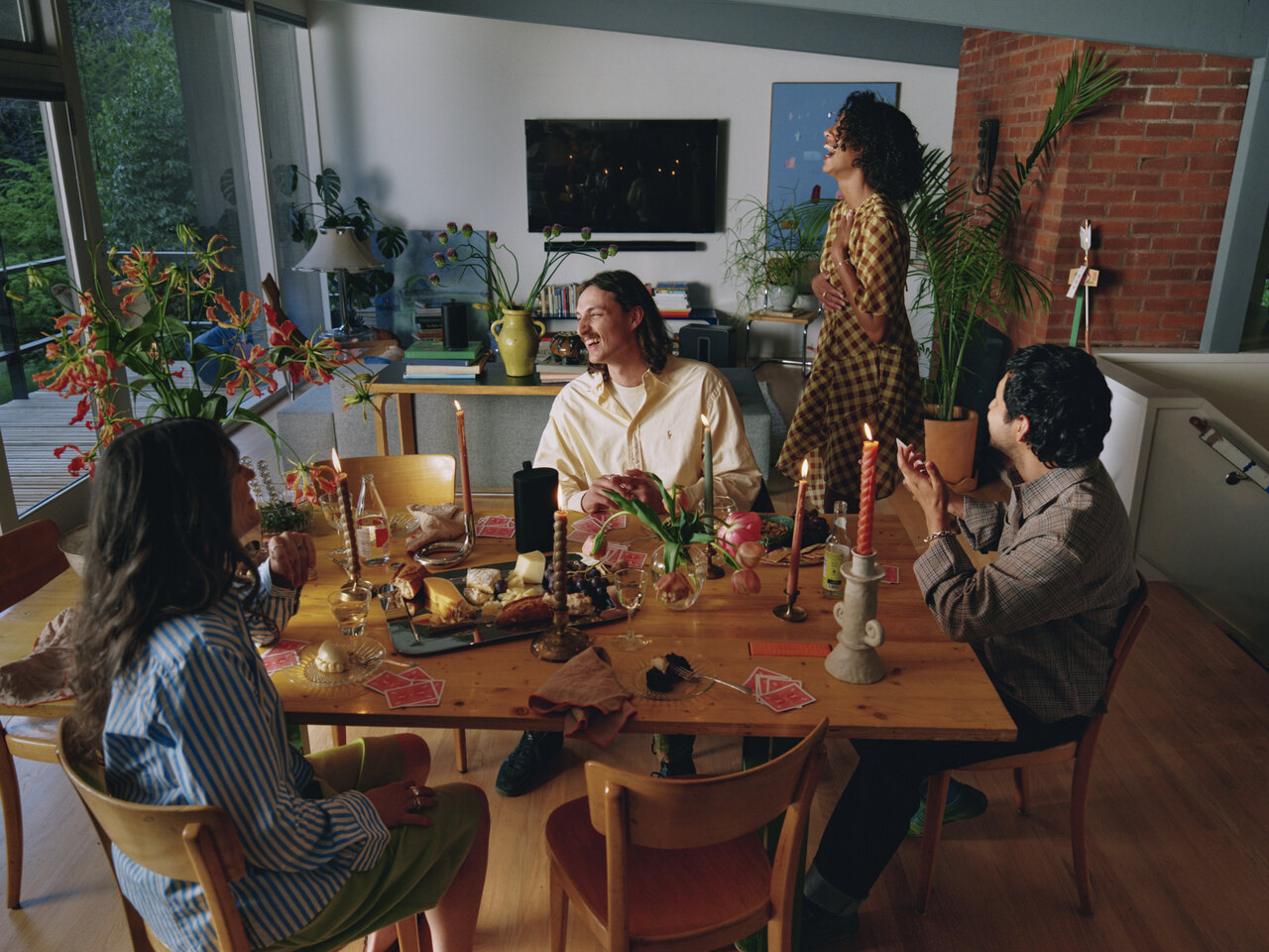 A group of friends around a dining table in a room with Sonos speakers.