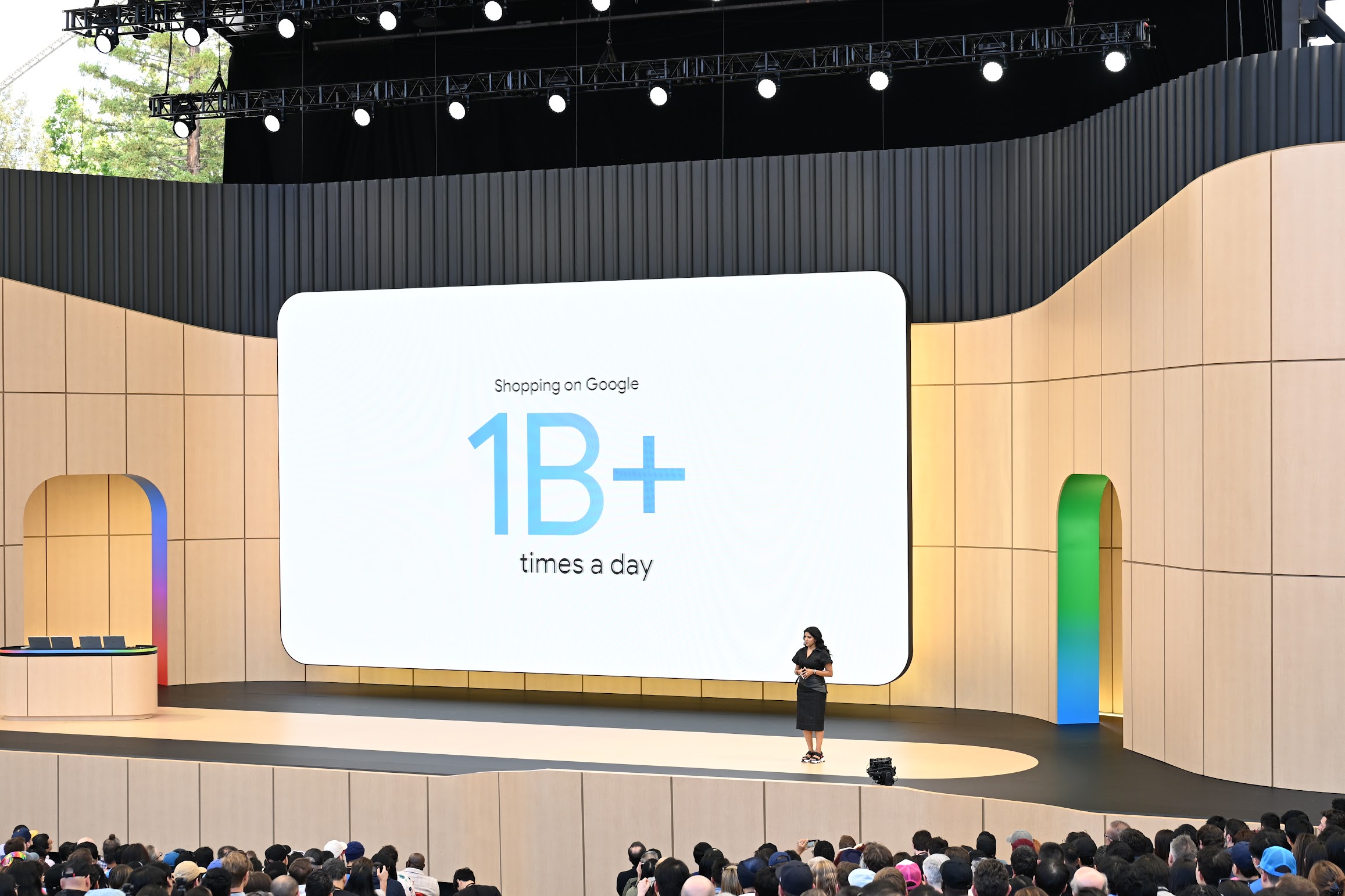 A presenter stands on the Google I/O stage before a screen about shopping on Google, with the event audience visible in the foreground.