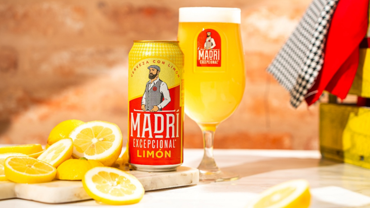 A can of Madrí Limón beside a glass of beer and cut lemons.